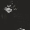a woman sitting in the dark holding a remote control